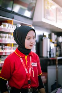 A young woman in hijab working as a cashier in a Palembang convenience store.