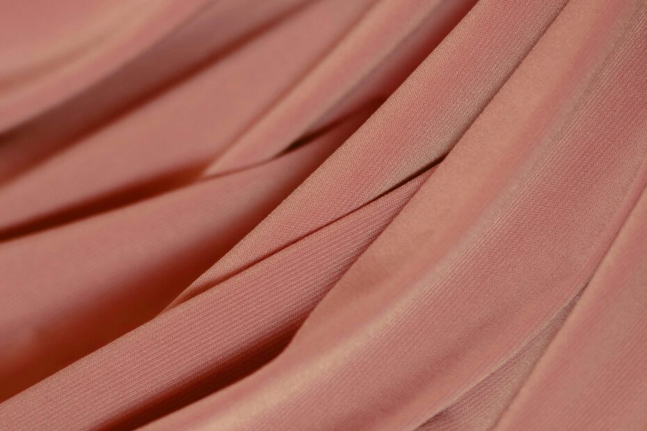 A soft and detailed view of flowing pink velvet fabric with elegant folds.