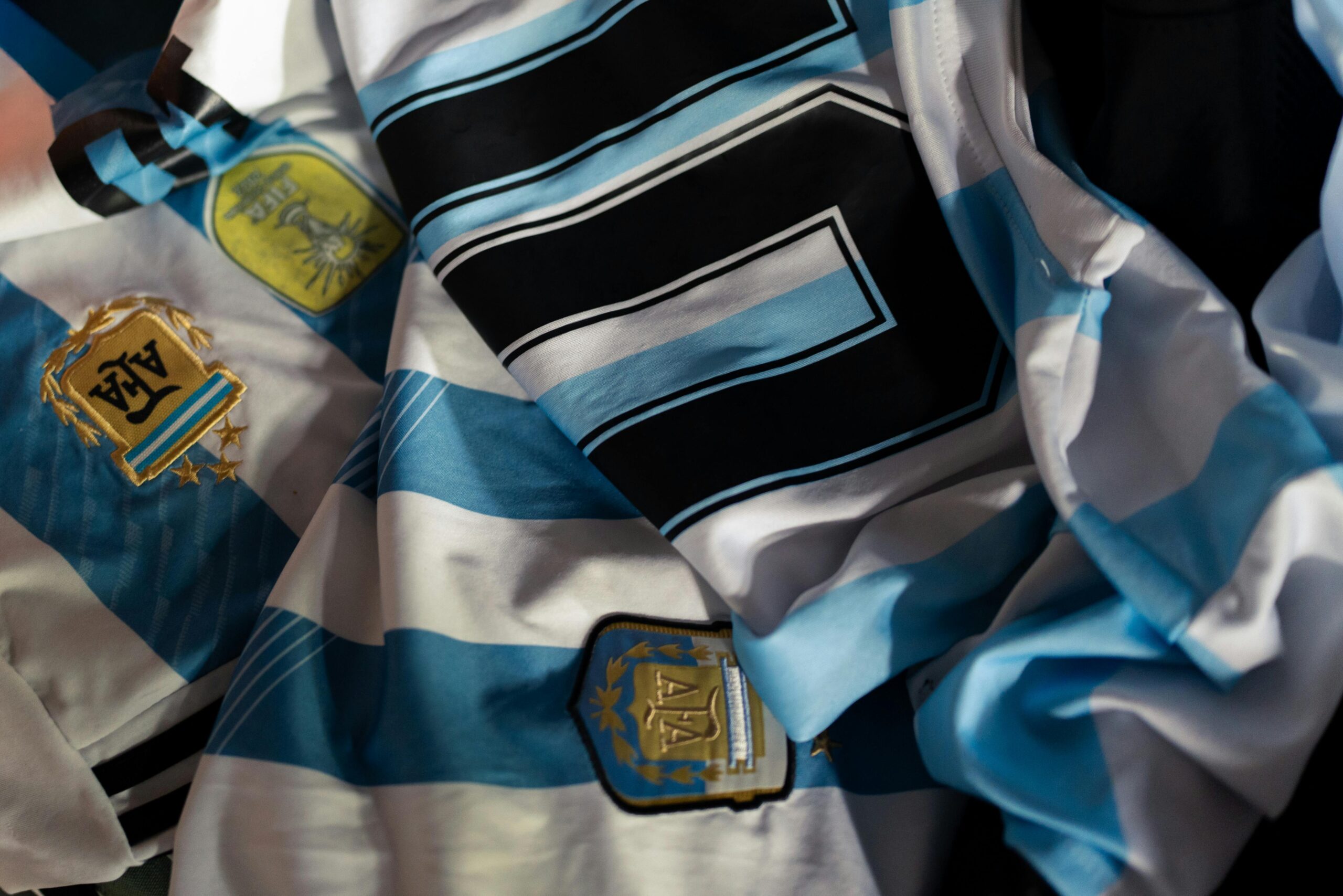 Close-up of Argentina soccer jerseys featuring national emblems and iconic designs.